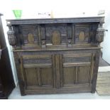 A mid 20thC Jacobean inspired, profusely carved and panelled oak court cupboard with a shelf top,