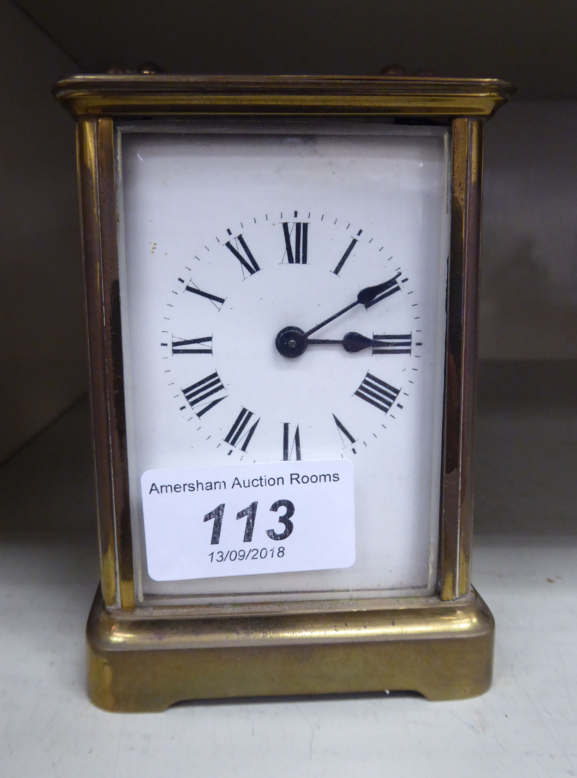 A mid 20thC brass cased carriage timepiece with bevelled glass panels and a folding top handle;