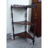 A late Victorian rosewood three tier corner what-not with a fret carved gallery upstand,
