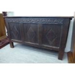 A late 18thC oak coffer with a carved tri-panelled front and a hinged lid,