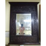 An early 20thC mirror, the bevelled plate set in a wide, panelled and relief carved oak frame,