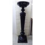 A mid 20thC Victorian style black painted wooden torchere, the circular top raised on a tapered,