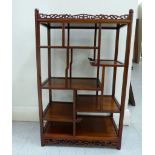 A modern exotic hardwood netsuke display stand, comprising an arrangement of staggered shelves,