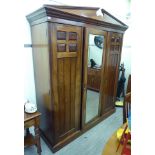 An Edwardian style mahogany wardrobe with a broken arch pediment, a central bevelled mirrored door,