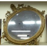 A late 19thC mirror, the oval plate set in a moulded gilt frame with shell,