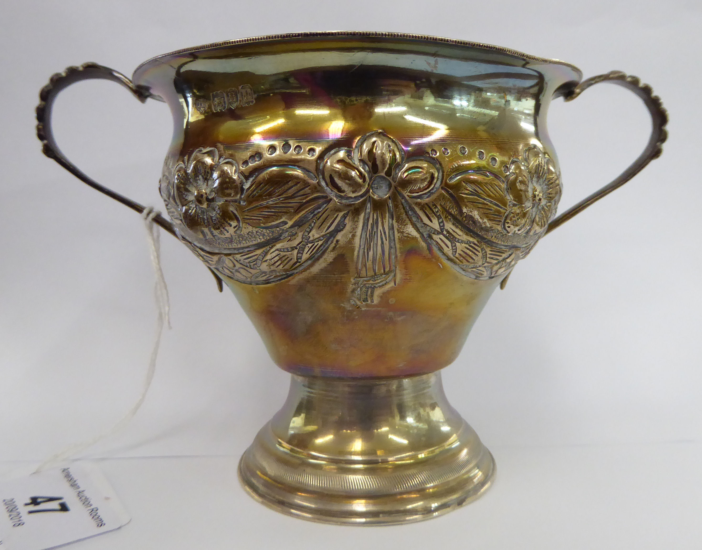 A silver bowl of pear design with a flared rim and opposing beaded loop handles, embossed flora,