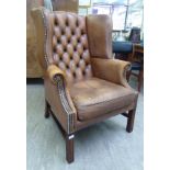 A modern Georgian design, buttoned brown hide upholstered wingback library chair,