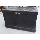 An early 20thC black painted pine tool chest with a hinged lid and straight sides and opposing iron