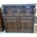 A mid 20thC Jacobean inspired, profusely carved and panelled oak court cupboard with a shelf top,