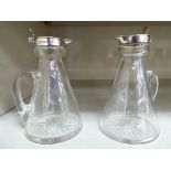 A pair of glass whisky tots of conical form with loop handles,