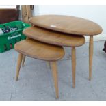 An nesting set of three Ercol light elm, pebble design coffee tables, raised on turned,