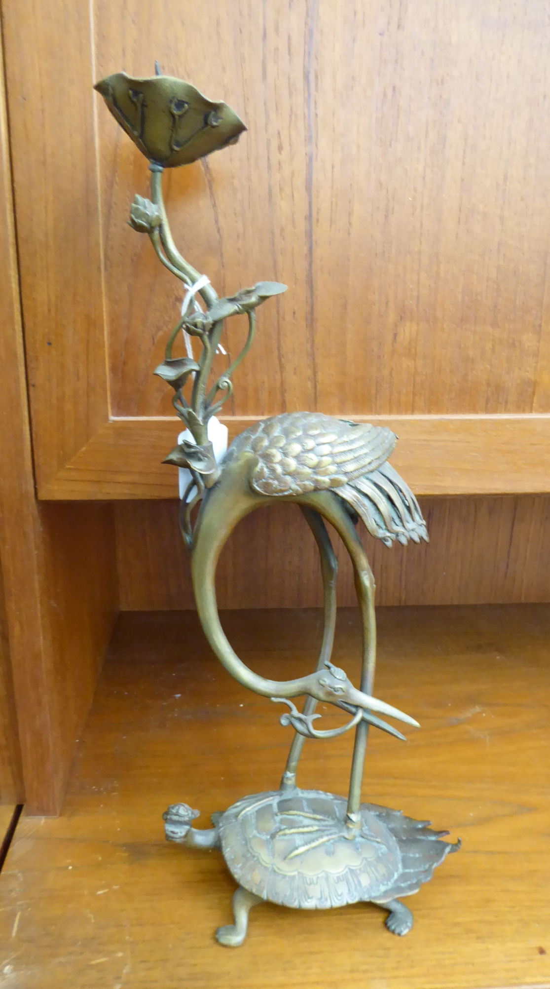 An early 20thC Chinese cast brass candlestick, fashioned as a tall flower beside a heron,