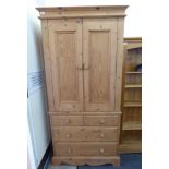 A modern waxed pine wardrobe with a pair of panelled doors, enclosing a hanging rail,