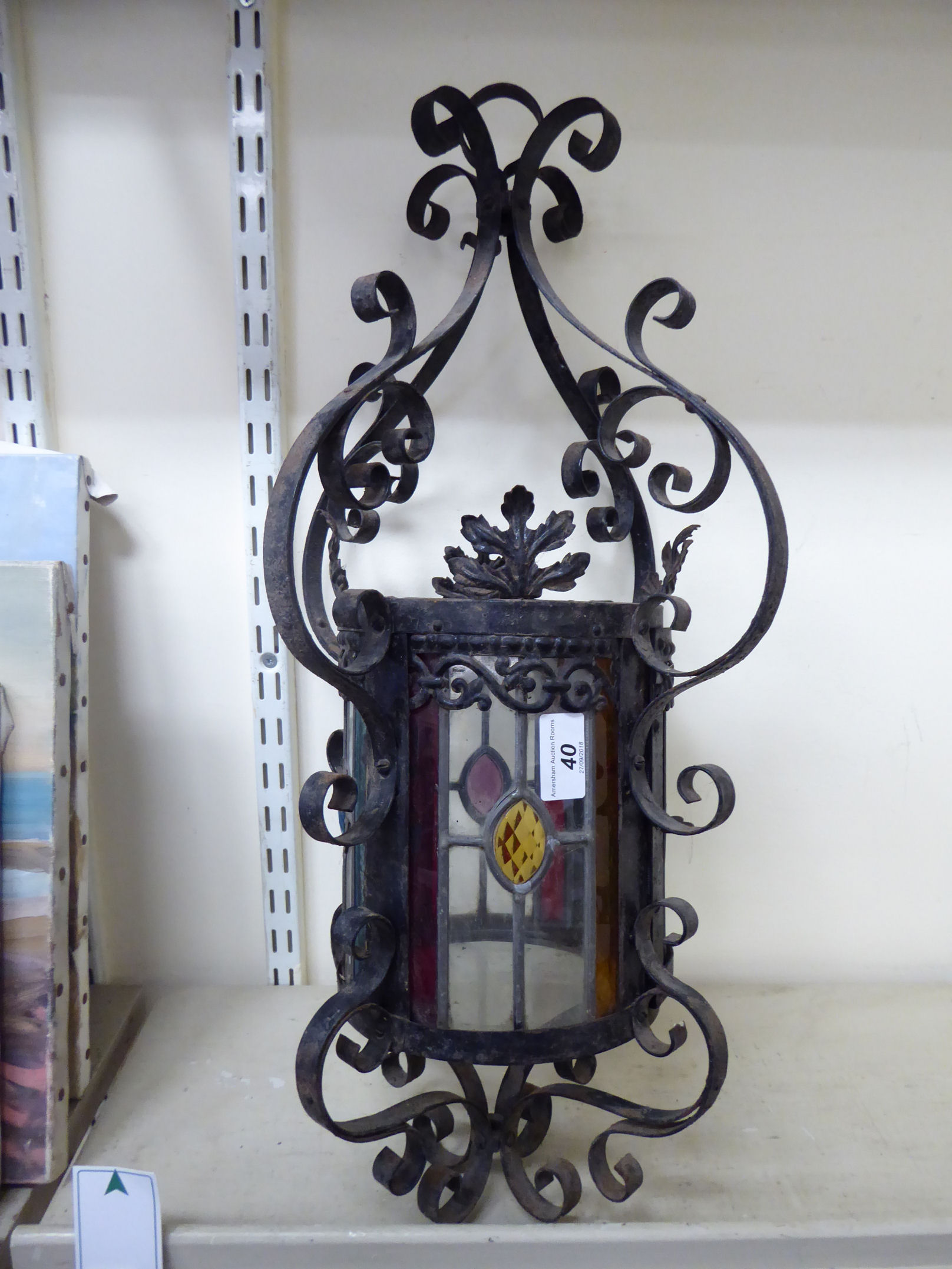 An early 20thC wrought black painted metal hanging lantern with clear and coloured lead glazed