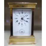 A modern lacquered brass carriage clock with bevelled glass panels and a swing top handle