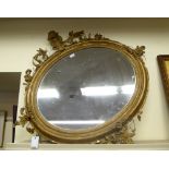 A late 19thC mirror, the oval plate set in a moulded gilt frame with shell,