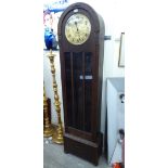 A 1920s stained oak longcase clock on a plinth and bun feet;