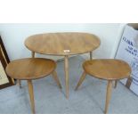 An nesting set of three Ercol light elm, pebble design coffee tables, raised on turned,