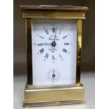 A modern lacquered brass carriage clock with bevelled glass panels and a swing top handle