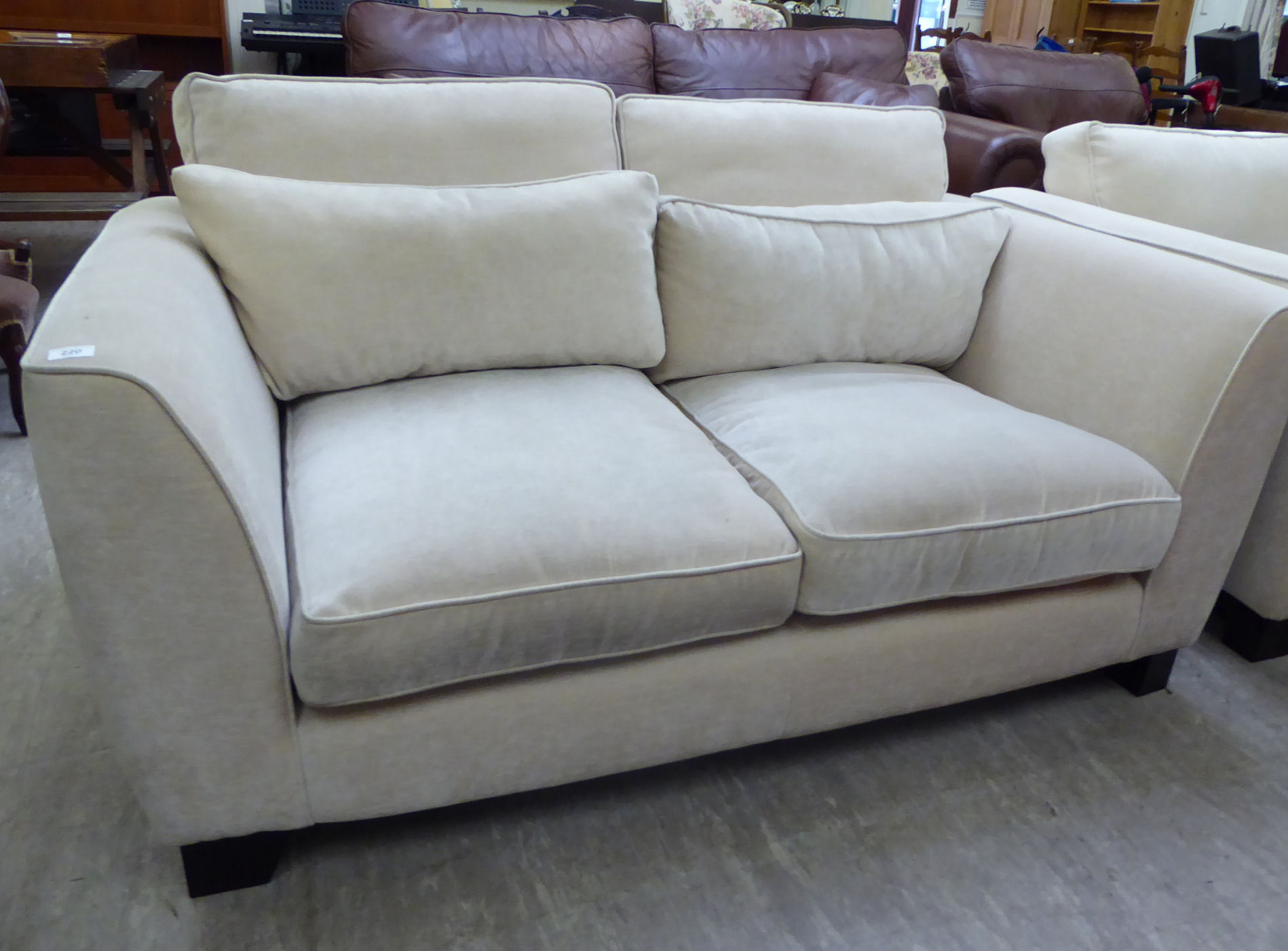 A modern two person settee, upholstered in cream coloured fabric,