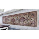 A Persian runner with three central medallions on a beige ground 124'' x 30'' RAM