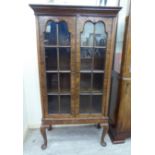A 1930s mahogany finished display cabinet with a pair of glazed doors,