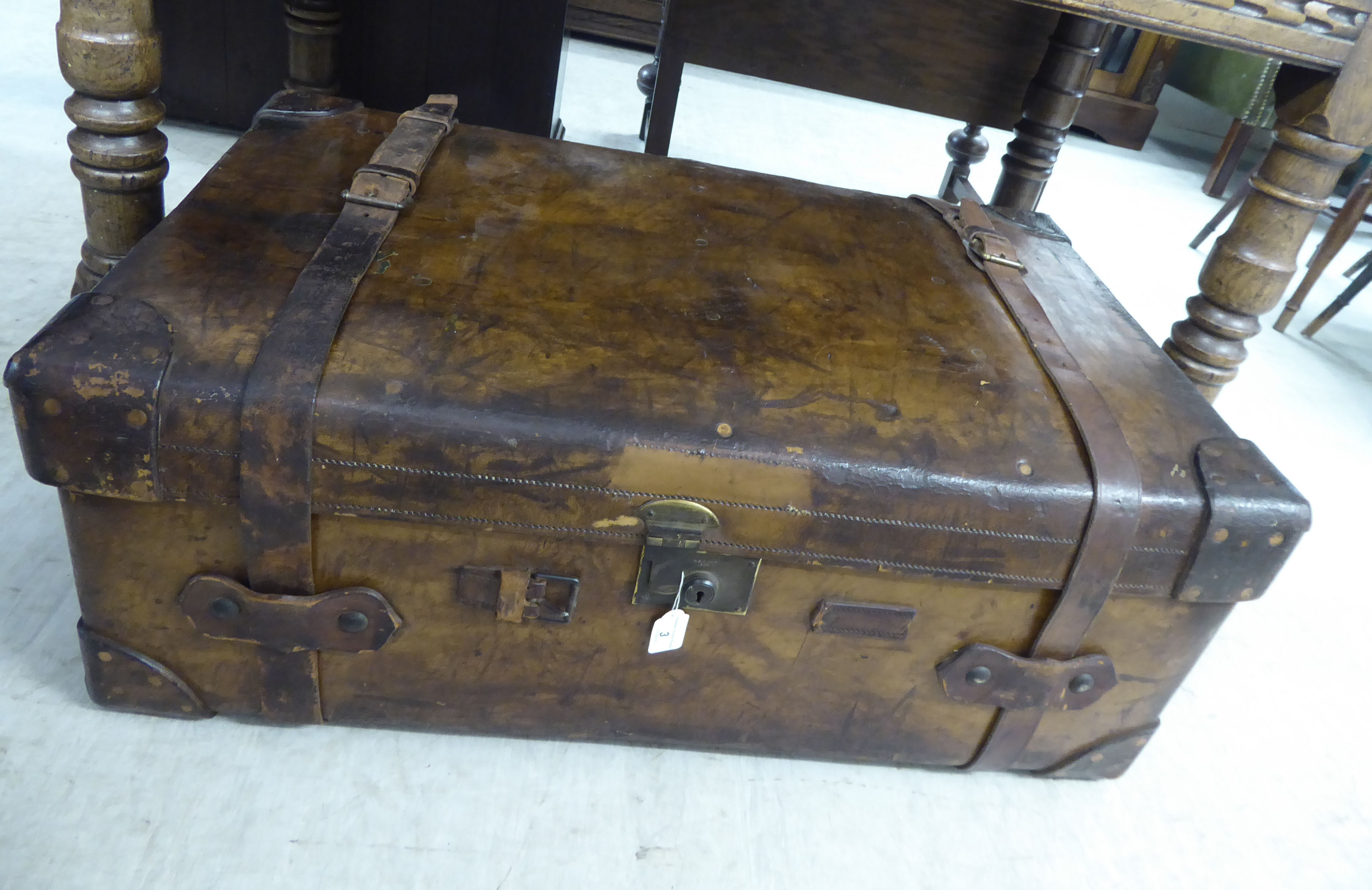 An early 20thC stitched brown hide cabin trunk with straight sides and a hinged lid,