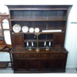 An early 19thC oak dresser, the wide, planked back superstructure with a level cornice, over open,