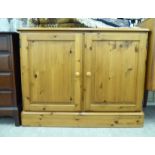 A modern waxed pine cupboard with a pair of panelled doors,