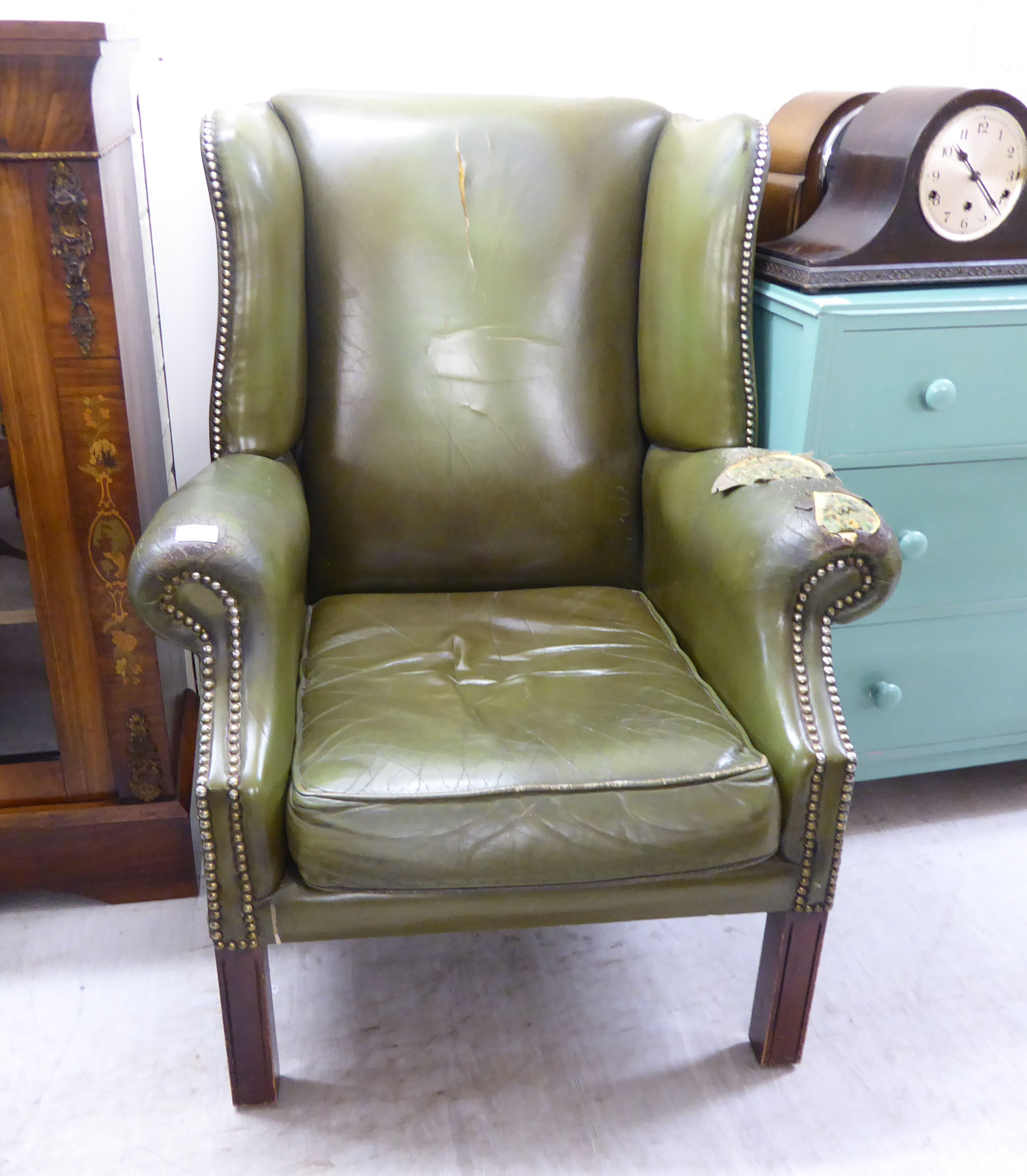 A mid 20thC Georgian style wingback armchair, stud upholstered in green hide,