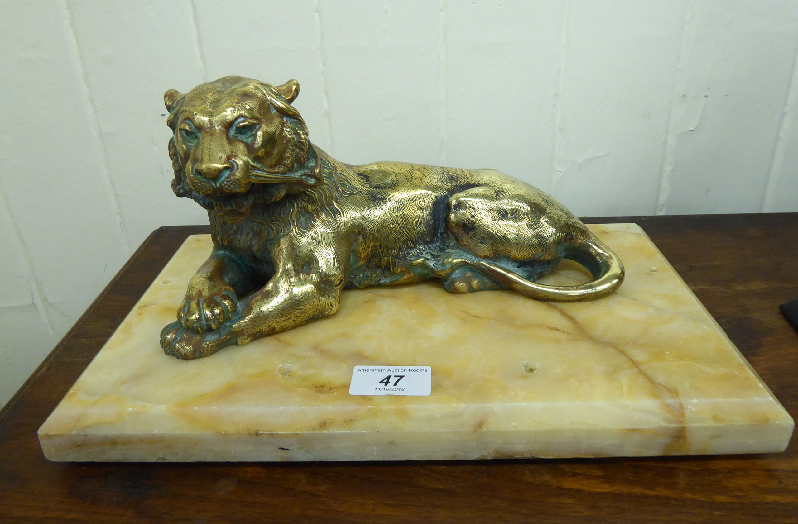 An early 20thC lacquered brass inkwell, fashioned as a seated lioness,