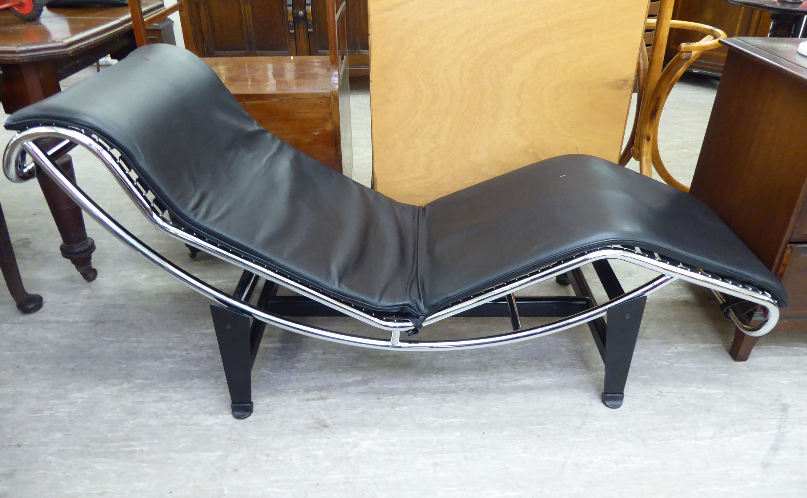A designer day bed/chair, the chromium plated frame with a black hide cushioned seat,