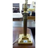 A modern brass table lamp with a reeded column and a Corinthian capital,