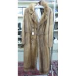 A knee-length blonde mink coat with a belt back,