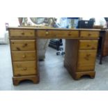 A modern pine nine drawer, twin pedestal desk, the top set with a tooled brown hide scriber,