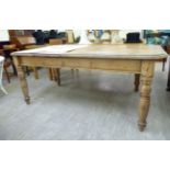 An early 20thC pine dining table, the planked top with canted corners, raised on ring turned,