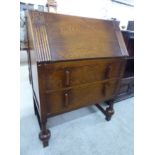 A 1930s stained oak bureau with a fall-flap, over two long drawers,