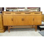 A 1970s Gomme teak sideboard with three frieze drawers, over four doors,