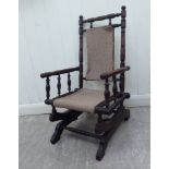 A late 19thC child's American design mahogany framed rocking chair with a spindled back,