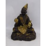 An 'antique' Asian part gilt painted cast iron figure, a man seated cross-legged,