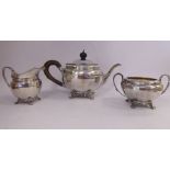 A three piece silver tea set of circular, bulbous and faceted form, on scrolled feet,