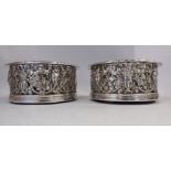 A pair of William IV silver wine coasters, profusely decorated with mask, fruiting vine,