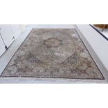 An Oriental silk carpet with a central motif, bordered by profuse flora, foliage,