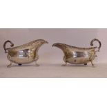 A pair of silver sauce boats with flared, gadrooned rims and double C-scrolled,