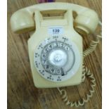 A 1970s cream coloured plastic telephone with a rotating dial, model no.