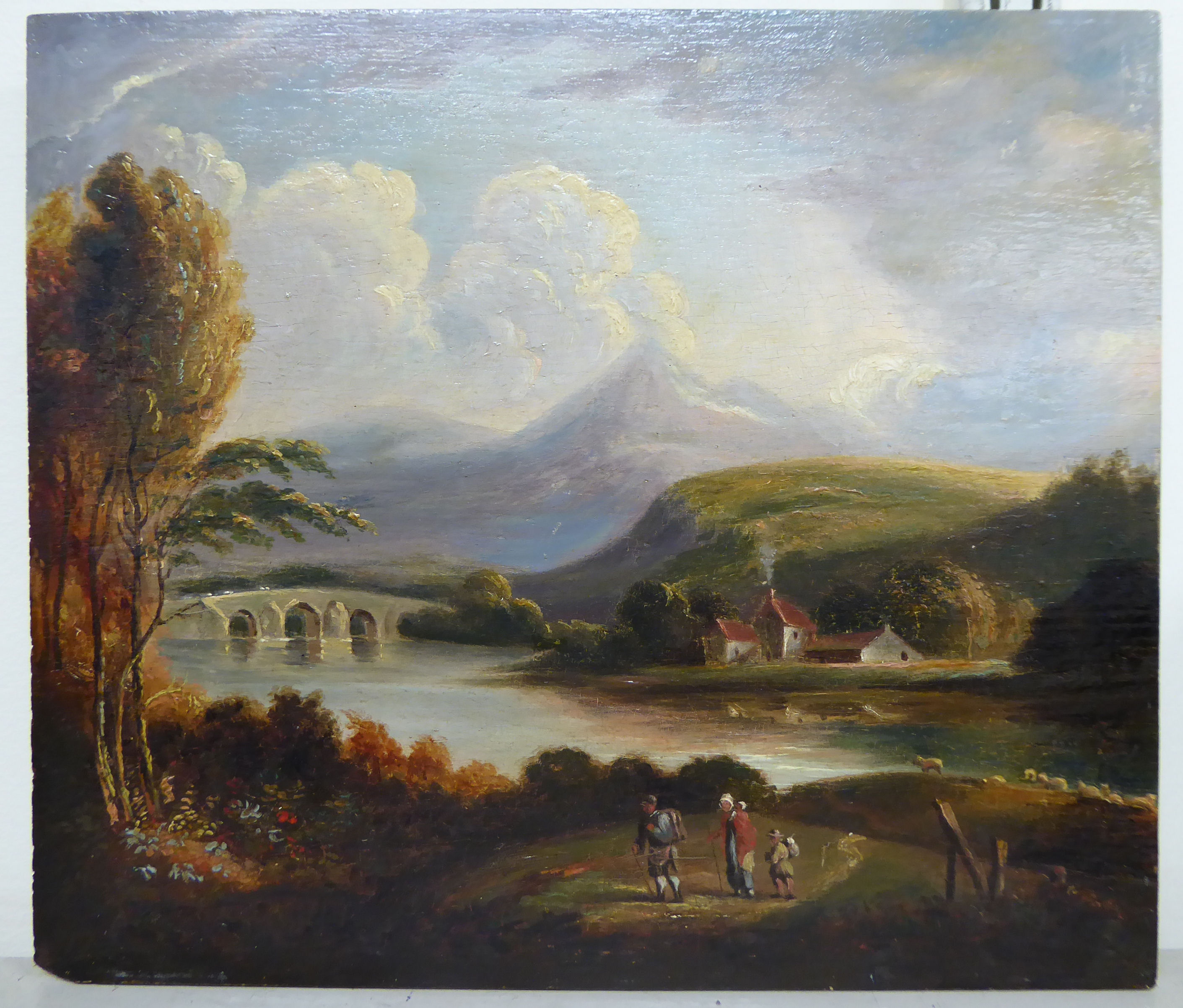 An early 19thC landscape with figures walking on a path with a bridge,