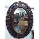 A mid 20thC mirror, the bevelled oval plate set in a shell,