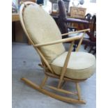 An Ercol stained beech framed chair with a spindled back and swept, open arms,
