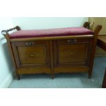 An Edwardian satinwood inlaid mahogany piano stool with an upholstered top, over two fall flaps,