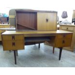 A 1970s Elliots of London teak dressing table, surmounted by a mirror, enclosed by sliding doors,